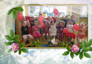 Na zdjęciu grupa dzieci. Dziewczynki trzymają czerwone balony.